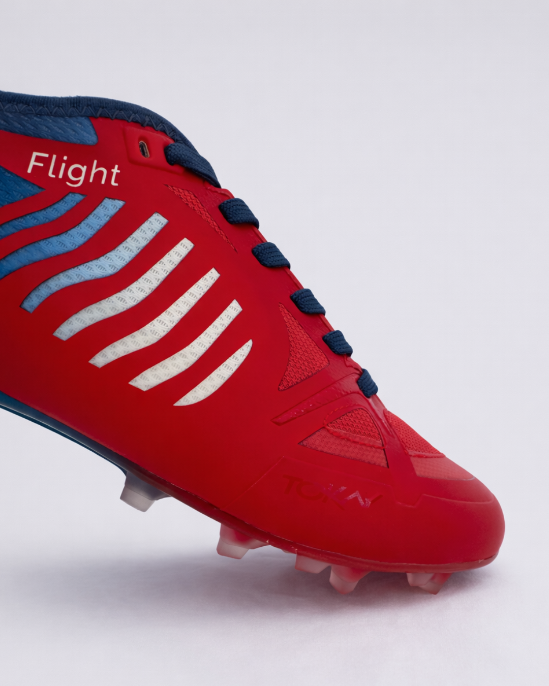 A close-up of a red athletic ultimate frisbee cleat cleat with navy blue laces and accents showing thze higher toebox fior extra comfort.