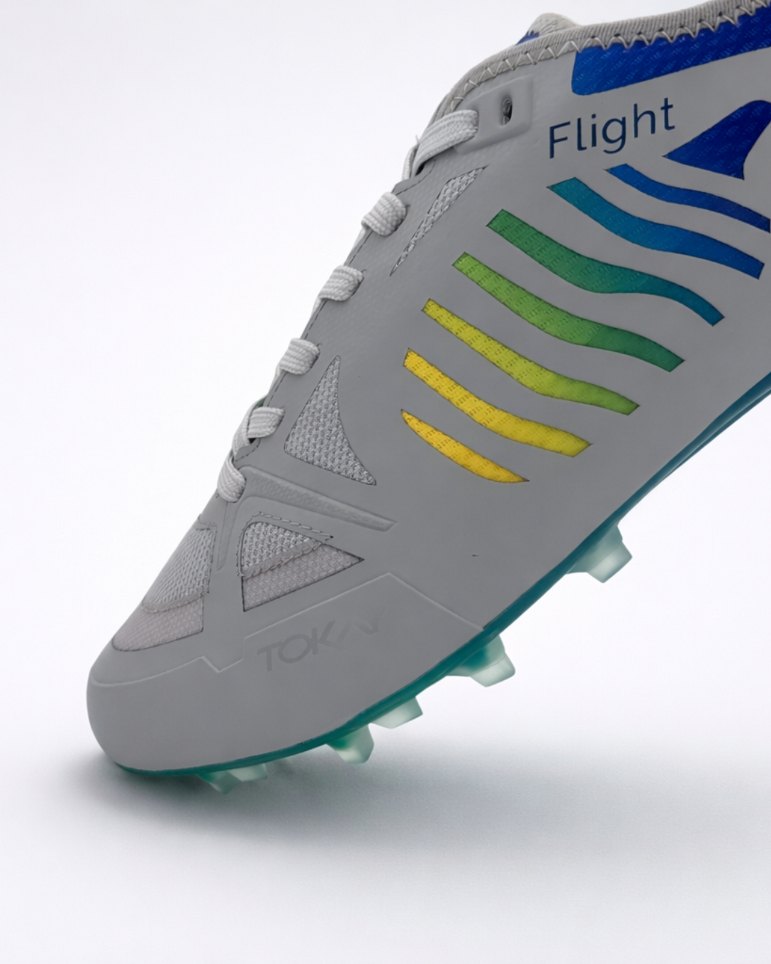A close-up of a gray ultimatefrisbee cleat with a rainbow gradient stripe pattern on the side, featuring the brand name 'Flight' and 'TOKAY' on the shoe, set against a clean white background.